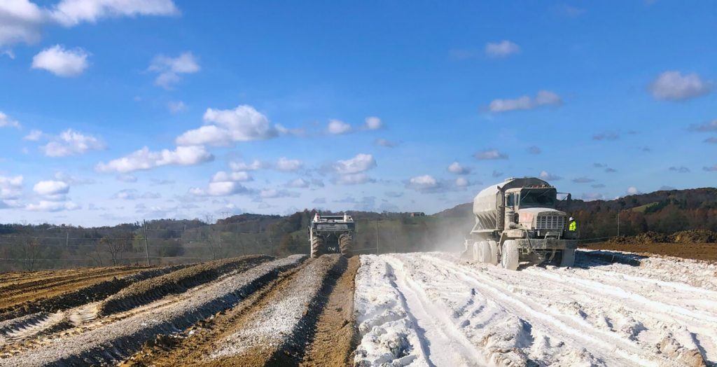 Construction trucks spreading lime on site