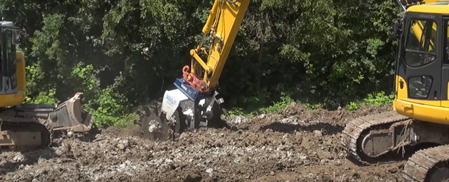 Backhoe with mixing attachment treating soil prior to placement